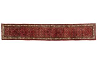 A red ground Hamadan strip runner with a central Herat pattern and a fishbone and running dog