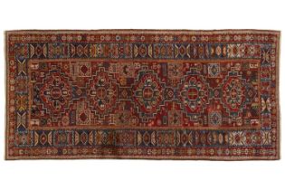 An antique red ground Shirvan carpet with five stepped diamond lozenges on a central pole, within