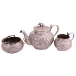 A white metal Burmese three piece tea set, the teapot with elephant finial and cobra handle, the