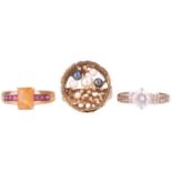 A collection of three rings, including a citrine ring with garnet set shoulders, the shank