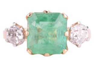 A three stone emerald and diamond ring, featuring an emerald measuring 8.2 x 7.8 x 4.7mm, flanked by