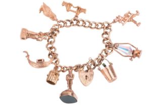 A 9ct gold charm bracelet with multiple charms, featuring a heavy link curb link bracelet in 9ct
