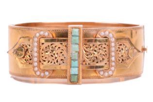 A Victorian buckle bangle in yellow metal featuring a turquoise and seed pearl set buckle with a