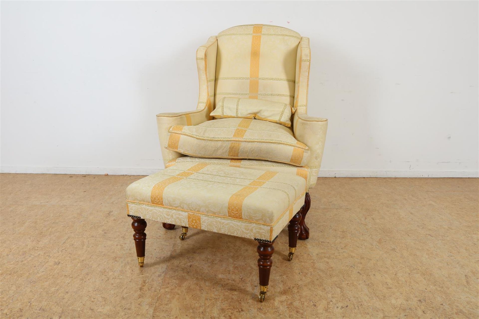 Armchair with yellow damask upholstery on ball claw feet with a matching footstool.