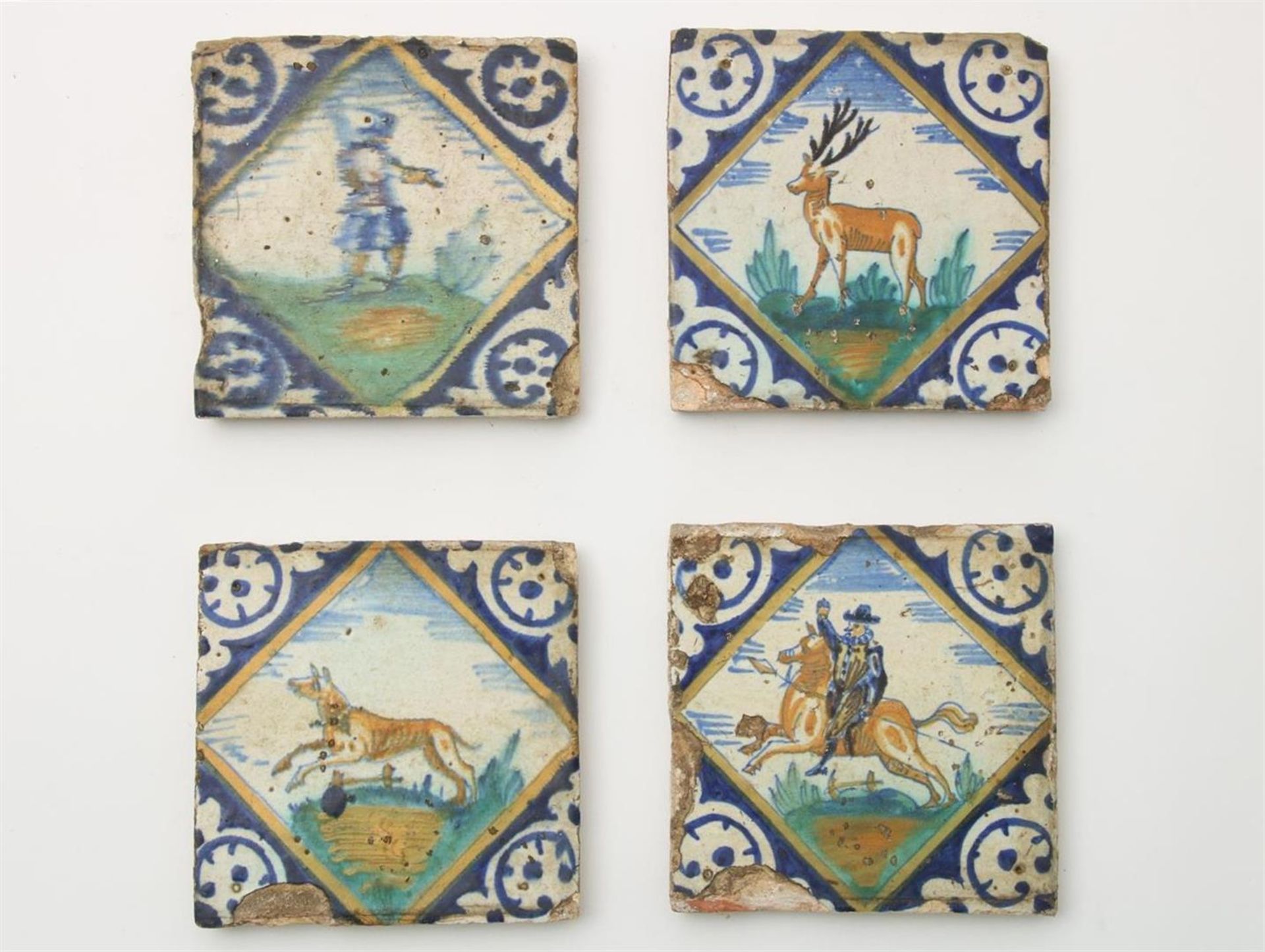 Four polychrome painted majolica square tiles: rider on horseback, soldier, deer and dog, circa