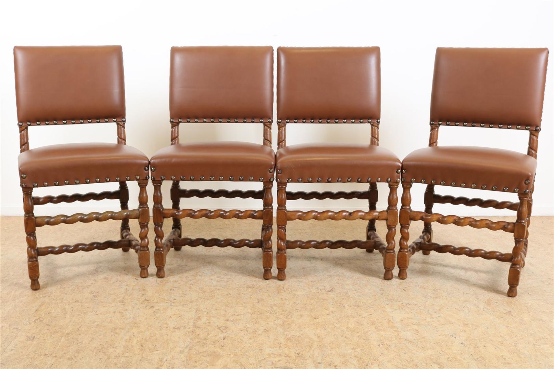 Series of 4 oak Renaissance-style chairs upholstered in brown leather.