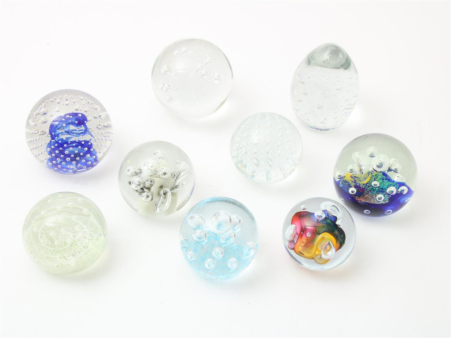 Series of 9 thick glass sphere and egg shaped paperweights, with enclosed bubble decor, possibly