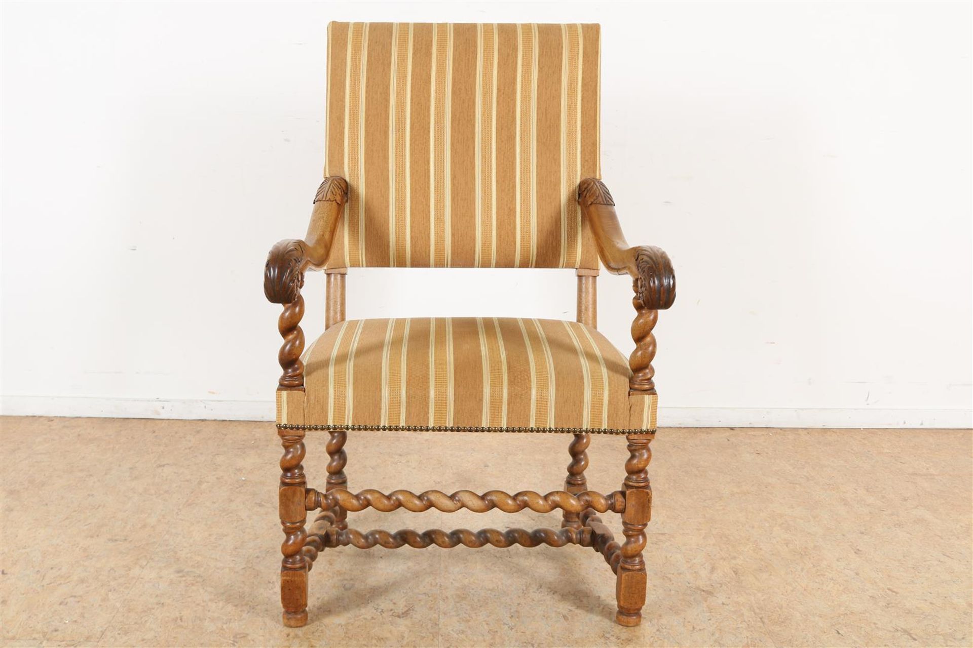 Walnut armchair with striped upholstery and carved acanthus leaves on the armrest.