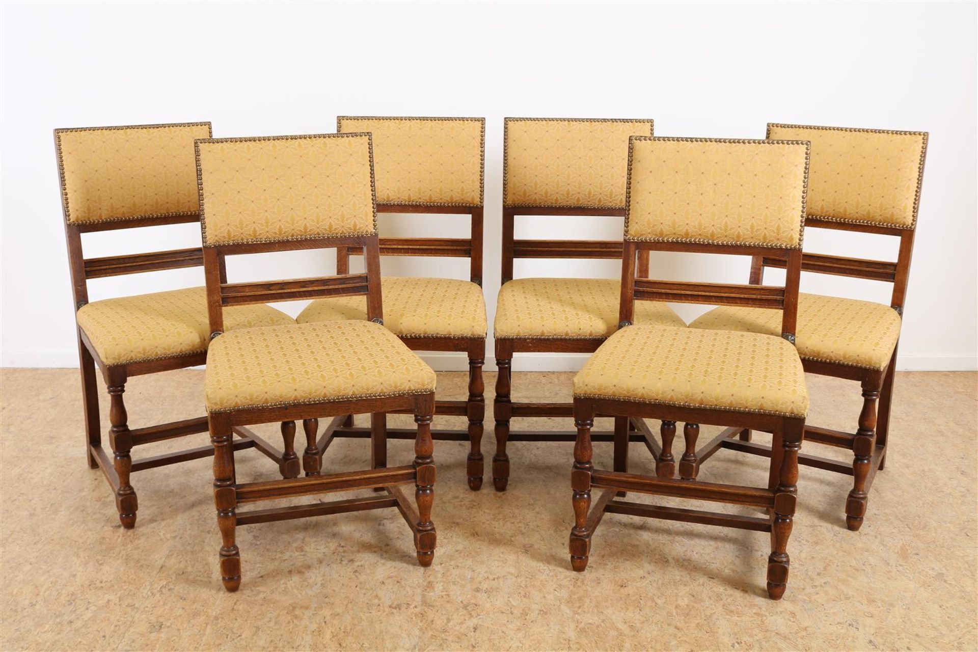 Series of 6 oak Renaissance-style chairs on vase legs connected by rules, early 20th century.