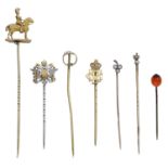 A collection of seven stickpins, the first with gold finial modelled as a French Carabinier...