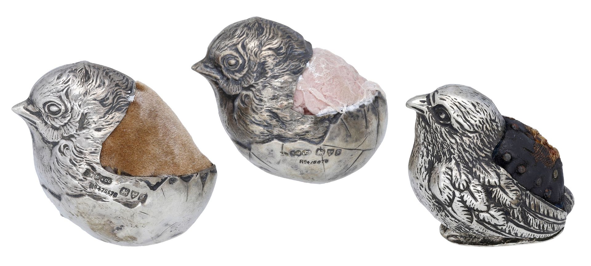 A matched pair of Edwardian silver chick pin cushions, the chicks hatching from their shells...