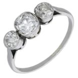 A diamond three stone ring, set with an old cushion-shaped diamond between old brilliant-cut...