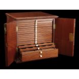 A mahogany coin cabinet, 27.5 x 27 x 25.5cm, comprising 16 trays single-pierced to house a t...