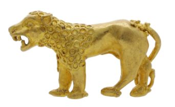 An antique cast gold miniature model of a lion, statant, with curled tail, the well-defined...
