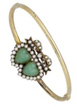 A late 19th century double heart hinged bangle, set to the front with two heart-shaped green...