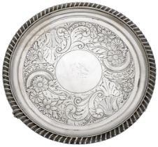 A George IV silver waiter, centred with a crest, within a broad band of later engraved flowe...