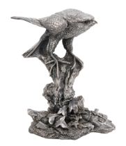 A silver falcon table centrepiece, the raptor perched on an ivy-strewn tree stump, resin-fil...