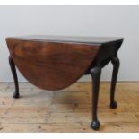 A GEORGE III MAHOGANY GATE-LEG TABLE, oval top with two drop leaves, on four Acanthus carved Queen