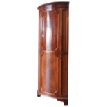 A 19TH CENTURY MAHOGANY CORNER WARDROBE / HALL CUPBOARD, bowed form with a single door enclosing