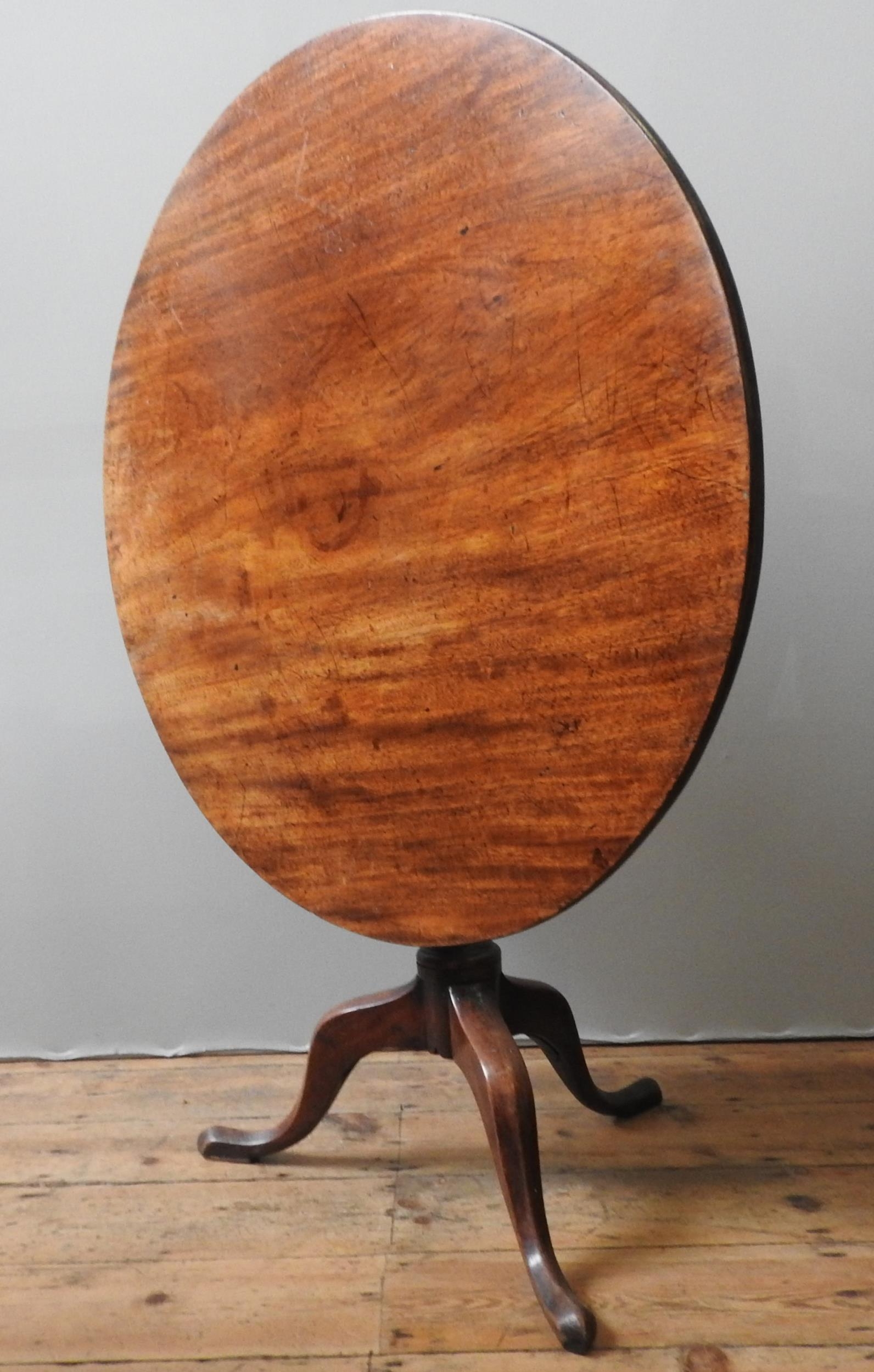 A GEORGE III MAHOGANY TILT TOP TRIPOD TABLE, the circular single piece top sat atop a turned