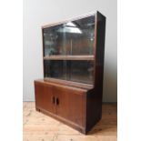 A MODULAR MID CENTURY MAHOGANY BOOKCASE, with two top sections with sliding glass doors, sat atop