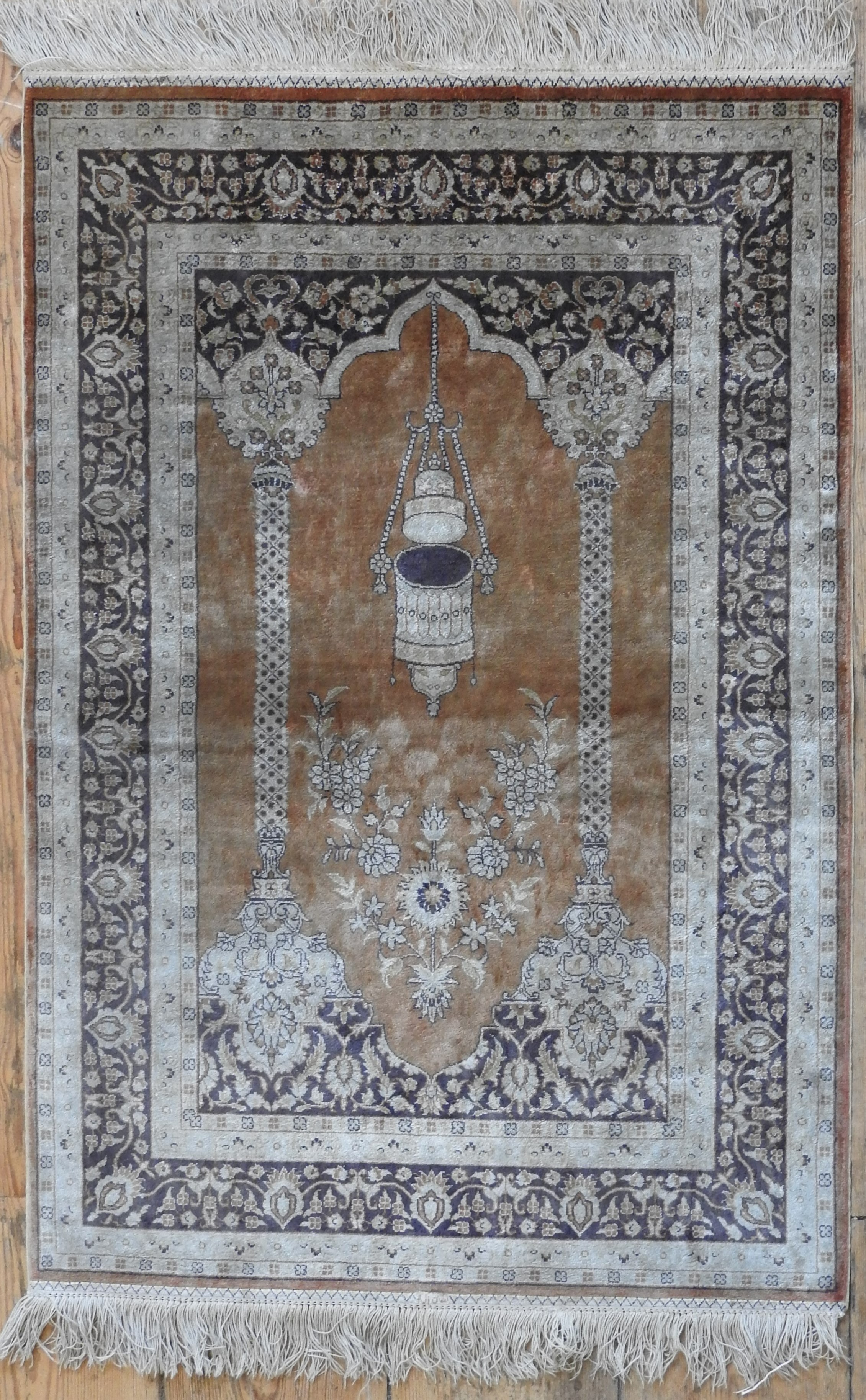 A PERSIAN SILK PRAYER RUG, depiciting temple arch and lantern, on a brown ground 94 x 61 cm