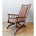 AN AMERICAN ROCKING CHAIR, a turned pillar oak frame raised on a sprung cradle base, the back
