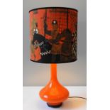 A RETRO ORANGE GLASS TABLE LAMP, compressed globular body with slender neck, the large drum shade