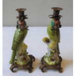A PAIR OF CERAMIC CANDLESTICKS IN THE FORM OF GREEN PARROTS, perched atop a naturalistic tree