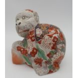 A JAPANESE IMARI FIGURE OF CROUCHING MONKEY, 20th century, modelled clutching two peaches, 18 cm