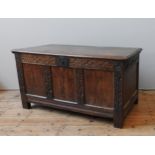 AN 18TH CENTURY OAK COFFER, simplistic rustic form, the frieze panels carved with scroll pattern and