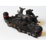 A CARVED BLACK FOREST INKWELL STAND, depicting a hunting scene featuring a fleeing deer and hound,