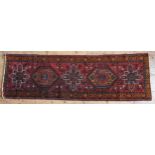 A PERSIAN HALL RUNNER, geometric pattern border and central motifs, on a deep red ground,  307 x