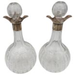 A PAIR OF SILVER MOUNTED GLASS DECANTERS, fluted globular bodies with silver collars / drip