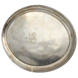 A LATE GEORGE III SILVER WAITER, ovoid form with bead moulded rim, raised on four scrolling