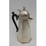 A SILVER HOT WATER JUG, tapered octagonal form with ebonised scroll handle and lid surmounted by