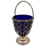 A SILVER WIREWORK SUGAR BOWL, with blue glass liner, rope twist swing handle, raised on a