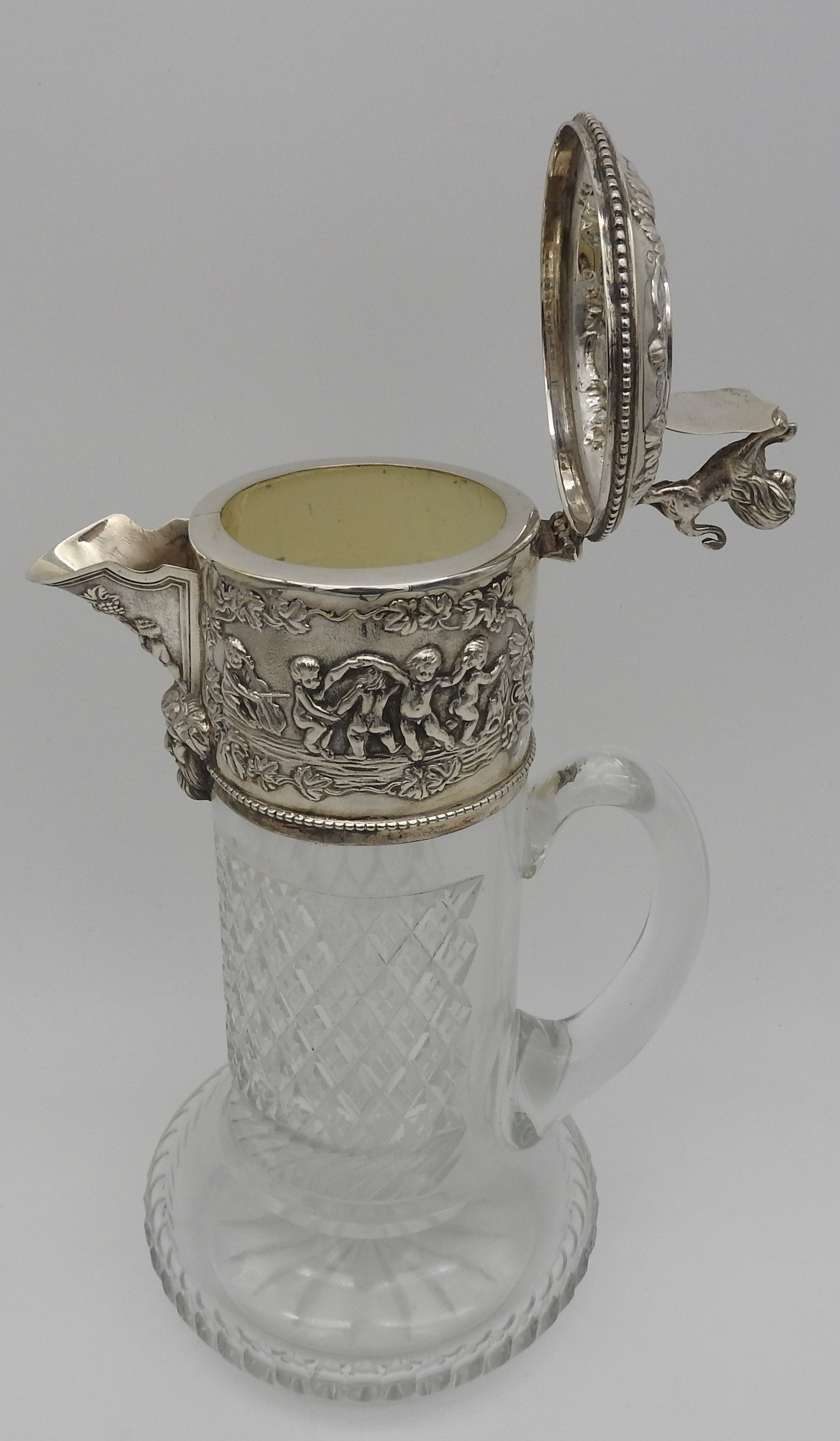 A SILVER MOUNTED CUT GLASS CLARET JUG, 20TH CENTURY, repousse decorated collar and lid depicting a