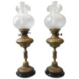 A PAIR OF ORNATE BRASS OIL LAMPS,LATE 19TH/EARLY 20TH CENTURY, the reservoirs with a band of