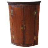 A 19TH CENTURY MAHOGANY CORNER CUPBOARD, CIRCA 1830, wall hanging bow front form, with three