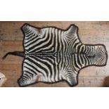 A SUPERB VINTAGE ZEBRA HIDE RUG, EARLY 20TH CENTURY, mounted on felt, bearing the label 'Rowland