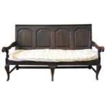 AN OAK COUNTRY SETTLE, EARLY 18TH CENTURY, a four panel back flanked by downswept arms, raised on