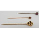 TWO RUBY SET YELLOW METAL STICK PINS, along with another gem stone set yellow metal stick pin, all