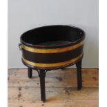 A GEORGE III MAHOGANY COOPERED WINE COOLER ON STAND, oval form with brass ring handles, raised on