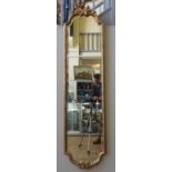 A 19TH CENTURY GILTWOOD FRAMED MIRROR, of slender prorportions with bevelled plate, the arched top