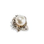 A PEARL AND DIAMOND RING set with a large central oval pearl