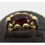 A HESSONITE 14CT GOLD GARNET SET RING, the oval garnet in an unusual scroll work setting, stamped