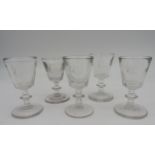 FIVE LATE GEORGE III GIN OR DRAM GLASSES, CIRCA 1820, the tapered heavy baluster bowls engraved with