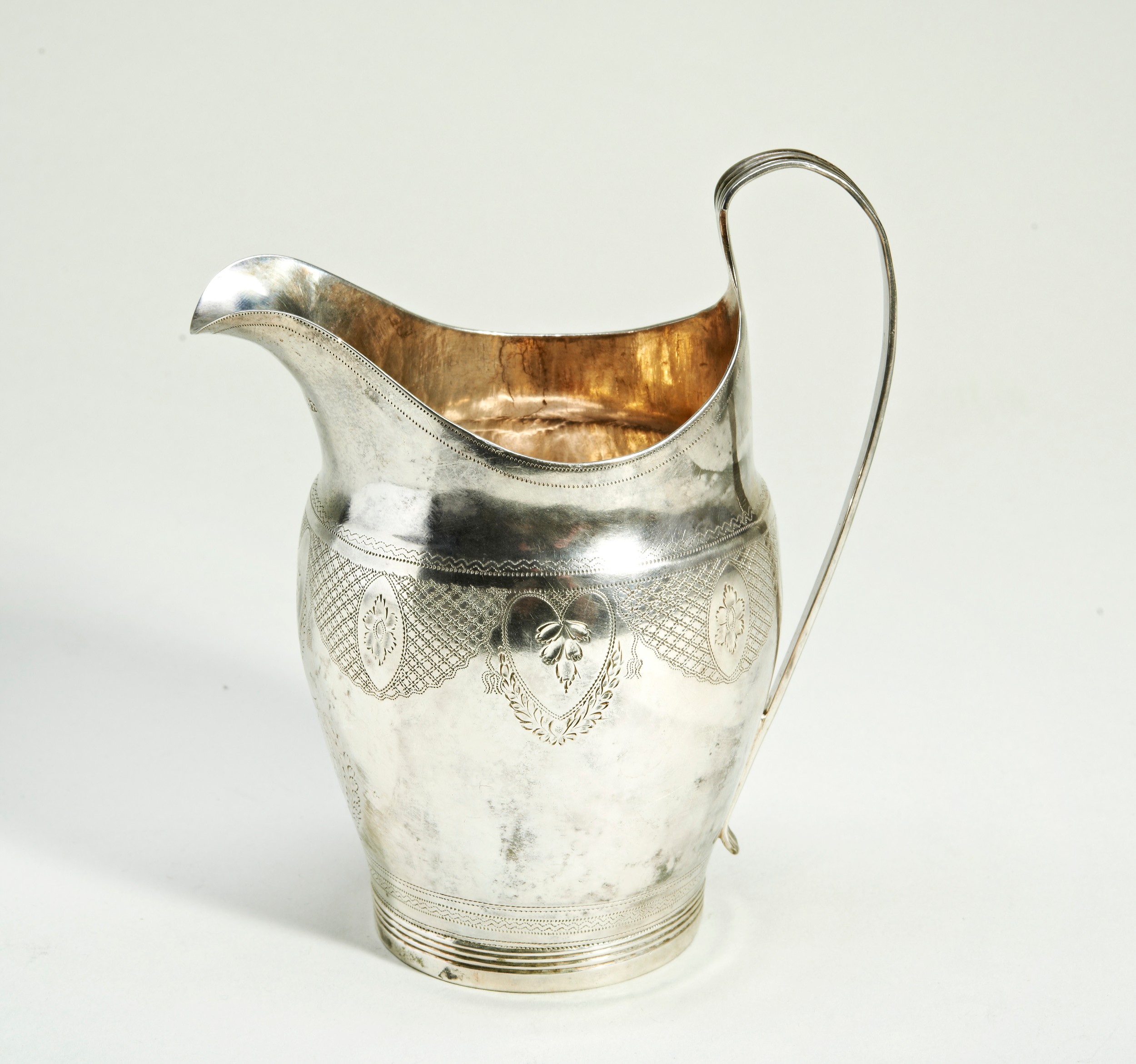 A GEORGE III SILVER CREAM JUG, helmet form, with bright cut reserves decorated with rosettes and