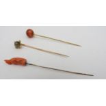 TWO HARDSTONE SET YELLOW METAL STICK PINS AND A CORAL STICK PIN, (untested) the coral set stick